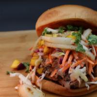 Hawaiian Butt Sandwich · Shredded smoked pork topped with mangoes, cilantro, onions, and slaw drizzled house sauce.