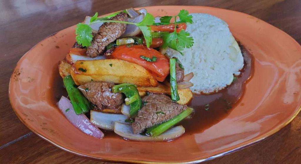 LOMO SALTADO` · Traditional Peruvian style stir fry beef tenderloin mixed in with potato fries, tomatoes, cilantro and served with rice & choclo.
