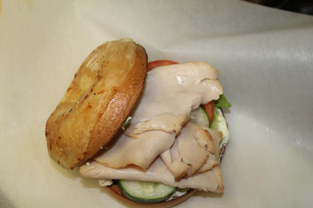 Yummy Turkey Sandwich · Smoked turkey, onion chive cream cheese, lettuce, tomato and cucumbers on an Asiago cheese bagel.