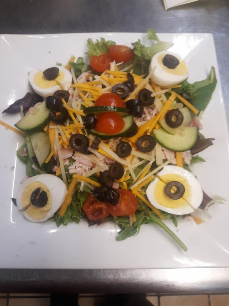 Chef Salad · Mixed greens, hickory smoked turkey, Black Forest ham, hard- boiled egg, black olives, cucumber, tomato, cheddar, and Swiss.