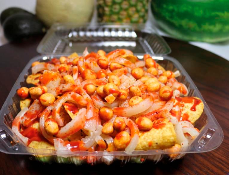 Tostilocos · A bag of tostitos chips on a plate filled with cucumbers, Jamaica, Japanese style peanuts, chamoy, valentina (hot sauce) and Tajin.