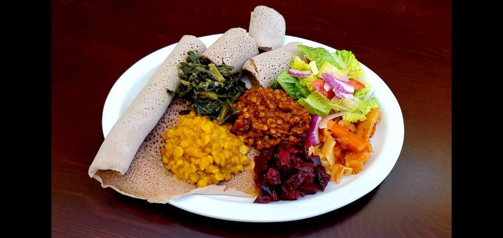 Ethiopian Vegetarian Combo (Vegan) · Ethiopian flat bread (Injera) combination of Misir wot(Red lentils kik Alitcha (yellow Split Peas) Atkilt wot ( vegetable Medley) Gomen wot (Collard Greens) beet and salad