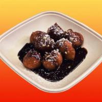 Lukumades · Donut holes dressed with honey and chocolate, topped with powdered sugar and walnuts.