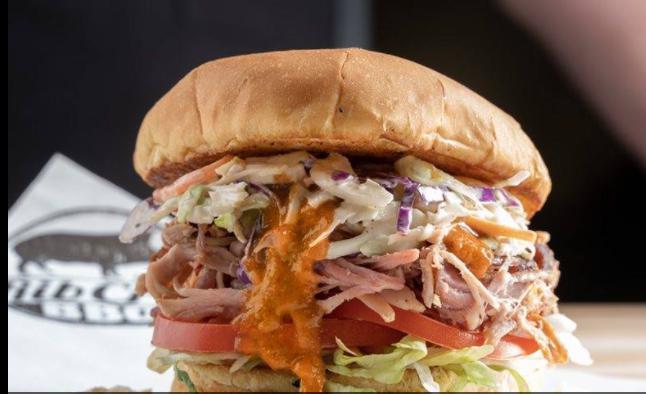 Carolina Pulled Pork Sandwich · Pulled pork topped with coleslaw, lettuce, tomato, and our Carolina mustard sauce on a bun. Served with one side and a pickle. Add protein for an additional charge.