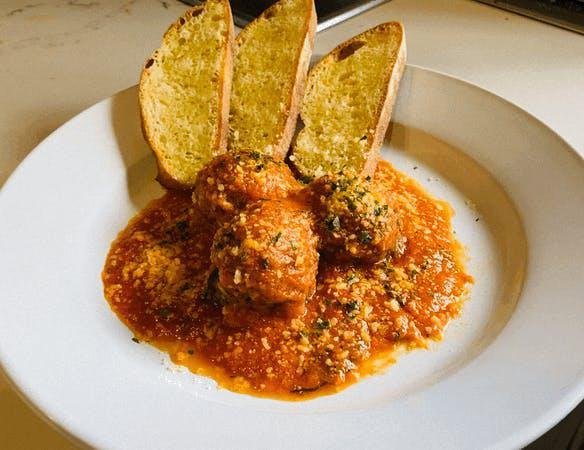 Polpette Al Sugo · Homemade beef meatballs with marinara sauce served with toasted garlic bread.