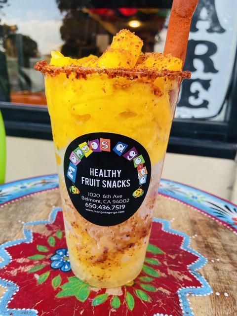 ChiMango · Mango trocitos (pieces of fruit), homemade mango syrup, shaved ice, chamoy, tamarind straw and garnished cup.