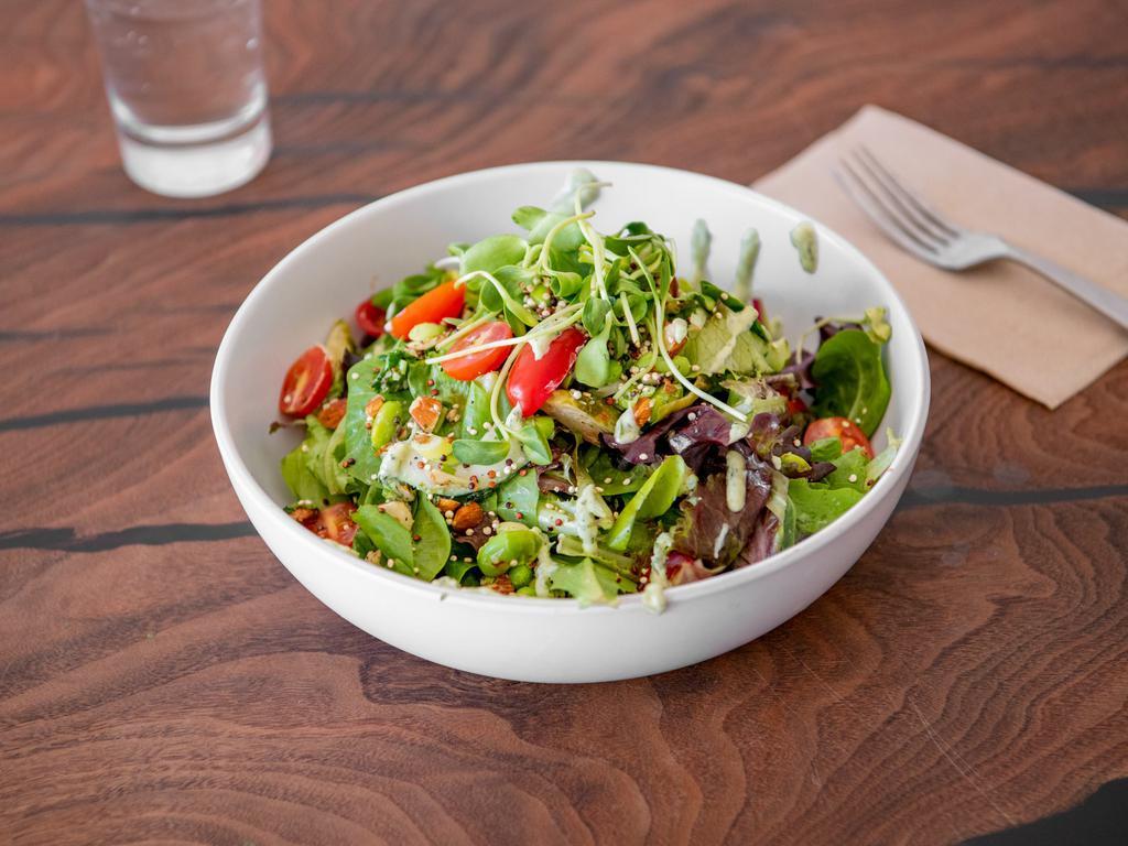 Green Goddess Salad · Lettuce blend, edamame, roasted brussels sprouts, cherry tomato, scallions, cucumber, crushed almonds with a cashew-based green goddess dressing, garnished with toasted quinoa.