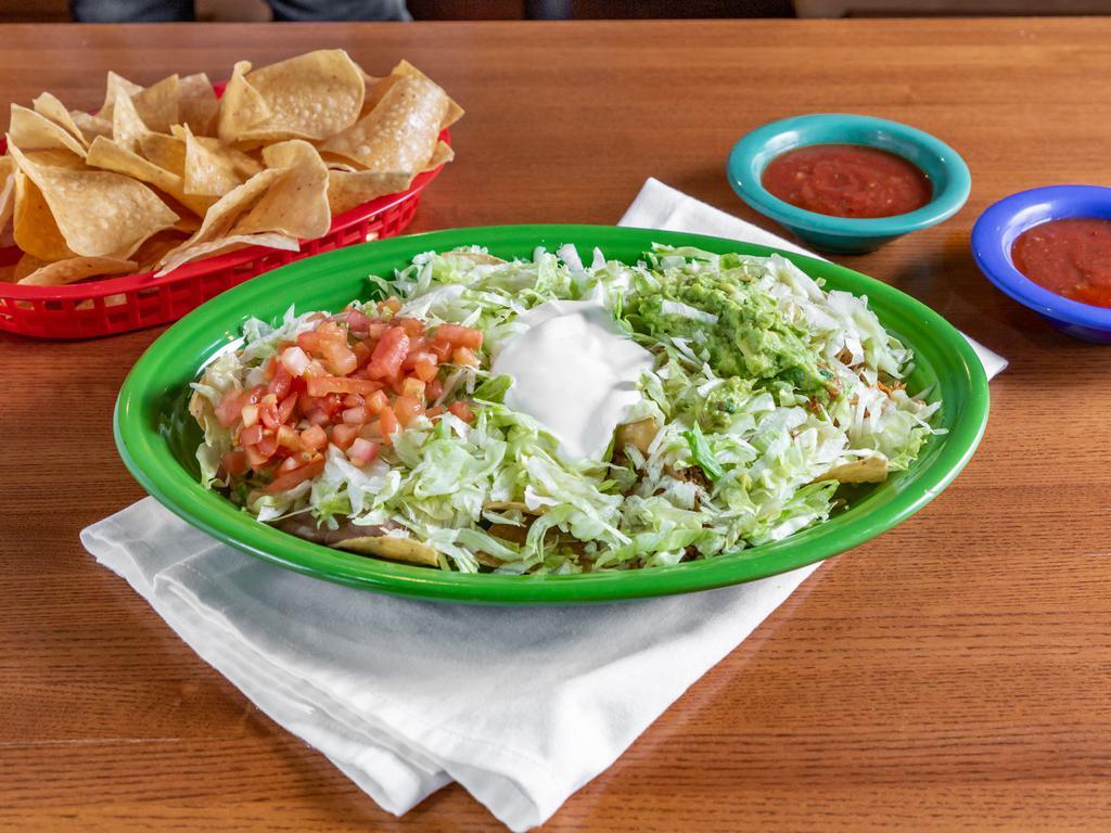 Full Order Nachos Supreme · A bed if crispy tortilla chips, smother with our flavorful white cheese dip, topped with chicken, beef, beans, lettuce, tomatoes, sour cream, and guacamole.