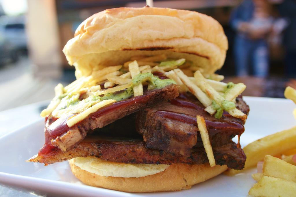 Brisket Sandwich · Smoked brisket on Brioche Buns topped with BBQ, green sauce, and potato sticks. Served with fries.