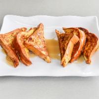 Challah French Toast · Three golden slices cut in 1/2 dusted with confectionary sugar, cooked with eggs, cinnamon p...