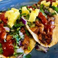 Al Pastor Taco · Pork marinated in chile and spice. 
Topped with diced red onions, fresh cilantro, pineapple...