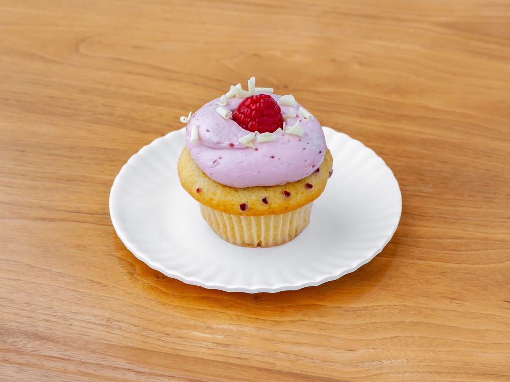 White Chocolate Raspberry Cupcake · Vanilla cake with raspberries baked in filled with a white chocolate mousse, topped with raspberry buttercream and white chocolate curls.