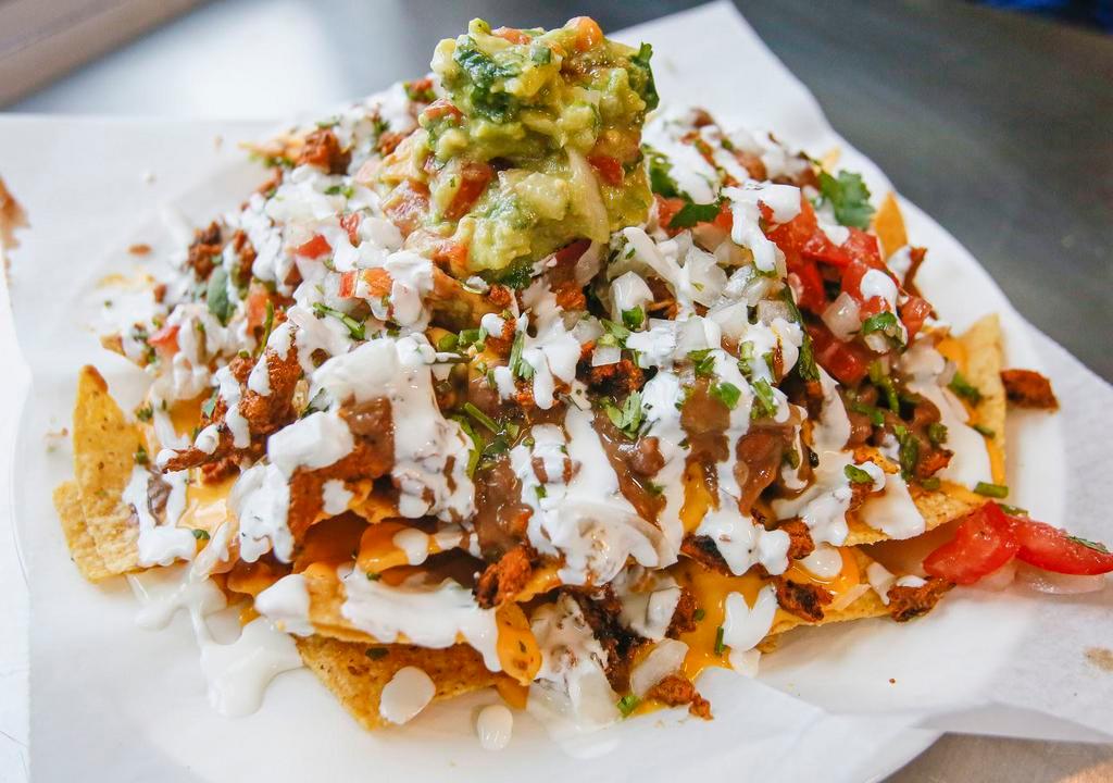 Nachos · Tortilla chips, choice of protein, beans, cheese, guacamole and jalapenos.