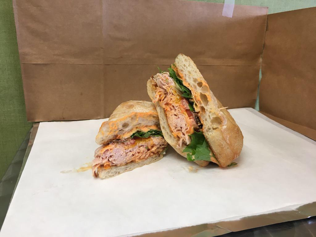 Turkey Rojo Sub · Smoked turkey with cheddar, greens, tomatoes and roasted red pepper aioli
on a ciabatta roll.