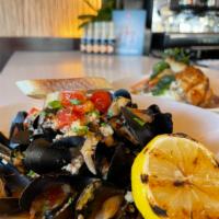 Mussels · steamed in a spicy and garlic tomato white wine sauce, topped with onion and couscous garnis...