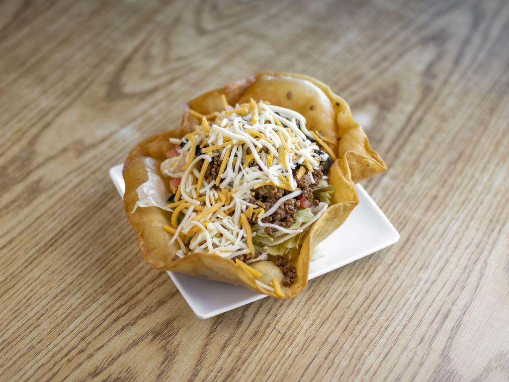 Taco Salad · Fresh greens in a freshly fried tortilla bowl topped with seasoned ground beef or chicken, cheddar cheese, tomato, black olives, onion, and choice of dressing.