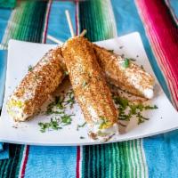 Elote de Feria · Corn on the cob topped with mayonnaise, Cotija cheese, and chili powder.