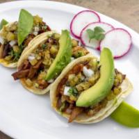 Al Pastor Taco · Marinated pork, chopped onion, cilantro, and avocado slice.
