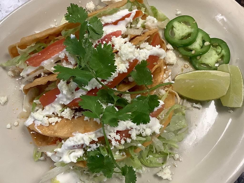 Crispy tinga tacos  · Chipotle tomato chicken served with crispy corn shells  toped with letters tomato sour cream and cilantro 