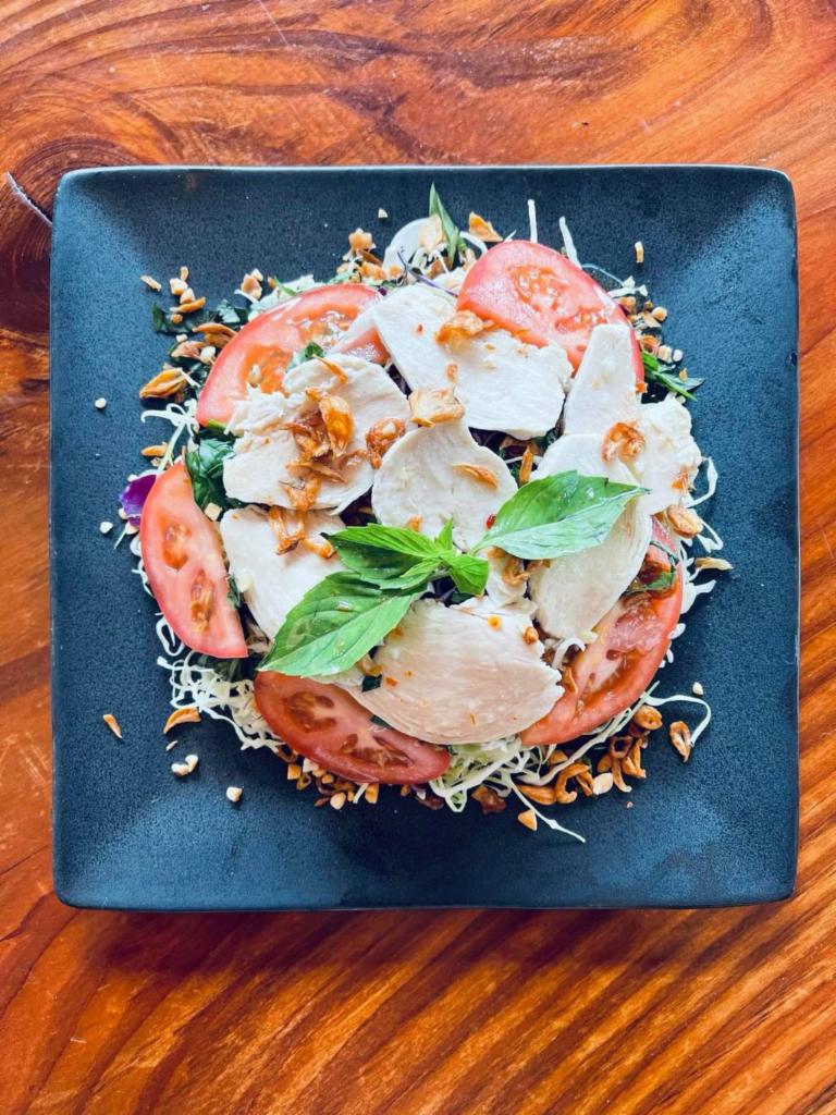 Chicken Cabbage Salad · Salad consisting of slices of chicken, shredded cabbage, and tomatoes accompanied by fresh basil, crispy shallots and peanut toppings with a dash of sour and spicy dressing.