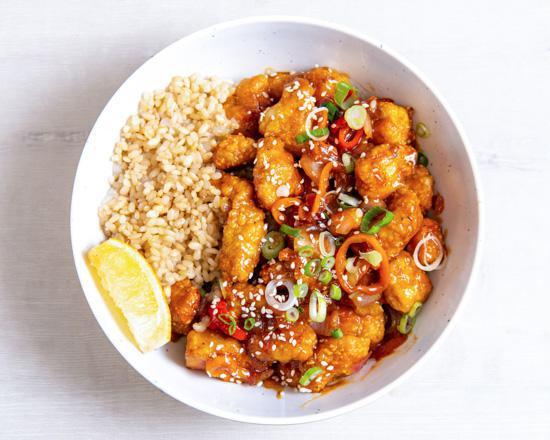 Gluten-Free Orange Chicken · Antibiotic-free, oven-fried chicken with charred peppers, caramelized onions, green onions, sesame seeds, and our house-made orange sesame sauce. Served with a lemon wedge, and a base of your choice. (gluten-free)