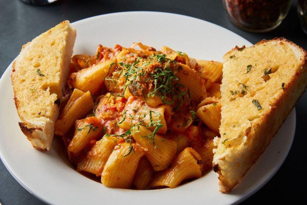 Rigatoni in Bolognese Sauce · Rigatoni tossed in a traditional bolognese sauce with ground sirloin, diced vegetables, topped with pangrattato, and parsley.