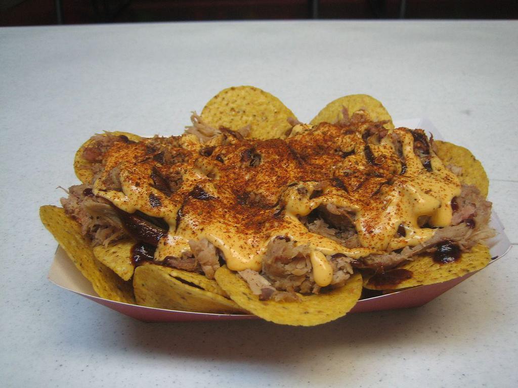 BBQ Pork Nachos · Tortilla Chips topped with our Slow Smoked Pulled BBQ Pork, Our Award Winning Competition Rib Rub and Original or Spicy BBQ Sauce, Nacho Cheese Sauce, & Jalapeños! (Unassembled).