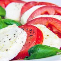 Caprese Salad · Fresh mozzarella cheese, sliced tomatoes, roasted red peppers, prosciutto and olives on a be...
