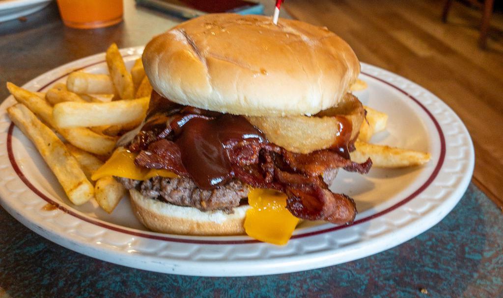 The Wrangler · A 6oz beef burger on brioche bun with cheddar cheese, bacon, onion ring, and BBQ sauce. Served with side. 