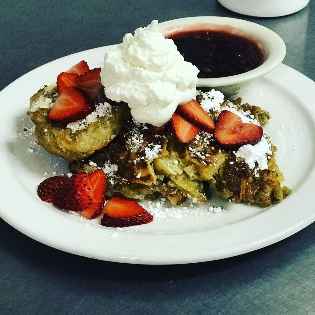 Croissant French Toast · 4 pieces of buttery croissant french toast served with seasonal fruit, lingonberry syrup and fresh whipped cream