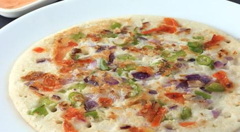 Tomato Uttapam · Uttapam is a thick pancake, with toppings cooked right into the batter. Uttapam is sometimes characterized as an Indian pizza.