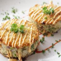 Crab Cakes · Crab cakes served with a drizzle of zamba sauce.