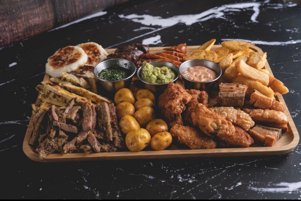Platter for Two · Grilled steak, grilled chicken breast, blood sausage, Colombian sausage, buffalo wings, fried pork belly, fried green plantains, yellow potato, cheese arepa, special sauce, guacamole and chimichurri. 