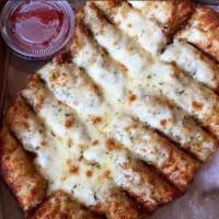 Cheesy Bread Sticks · Delightfully smothered in our signature white garlic sauce garnished with Parmesan, a dash o...