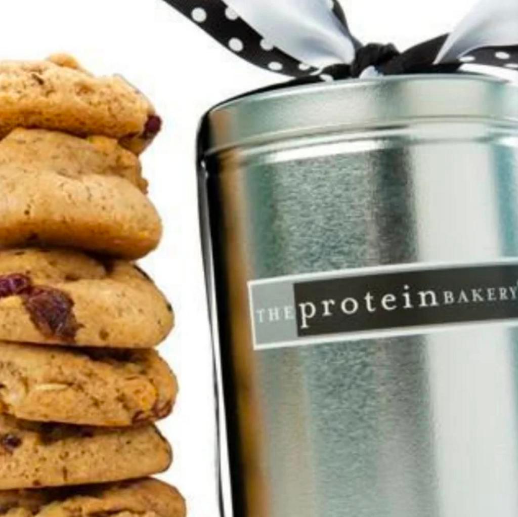 Cookie Pint Gift Tin · How else to satisfy your hunger than with one of our many cookie assortments? Treat yourself or someone who is just as deserving, to naturally delicious decadence. Sample our entire line of our protein-packed cookies. All our flavors are wheat flour-free, trans fat-free, gluten-free and baked in small batches. Your order is individually and artfully wrapped in a sleek gift tin. Starting at our bakery 'til they arrive at their new address, these guilt-free goodies are handled with the utmost care. (4 cookie two-packs) Protein: Up to 56 grams Certified KOF-K DAIRY KOSHER.

