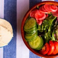 The Greek Goddess Salad · Artisanal Hummus, Fresh Tomatoes, Cucumbers, Pickled Red Onions, and Radishes on a Bed of Me...