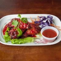12. Thai-Style Chicken Wings · Thai-style chicken wings served with a side of Sriracha sauce.