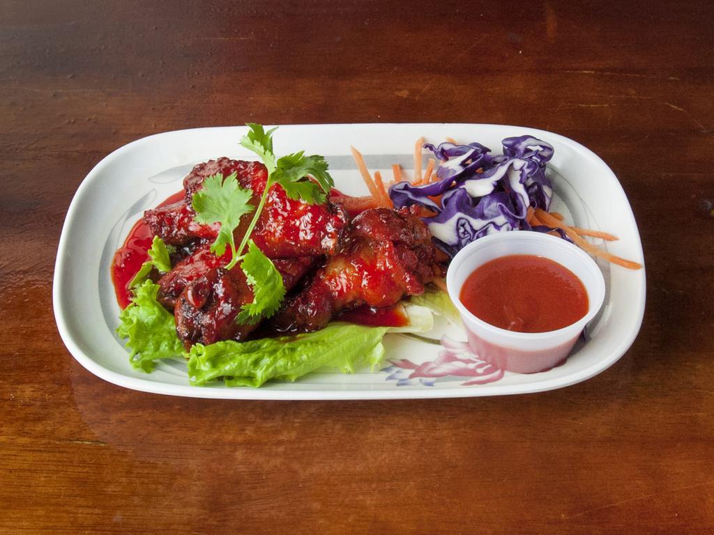 12. Thai-Style Chicken Wings · Thai-style chicken wings served with a side of Sriracha sauce.