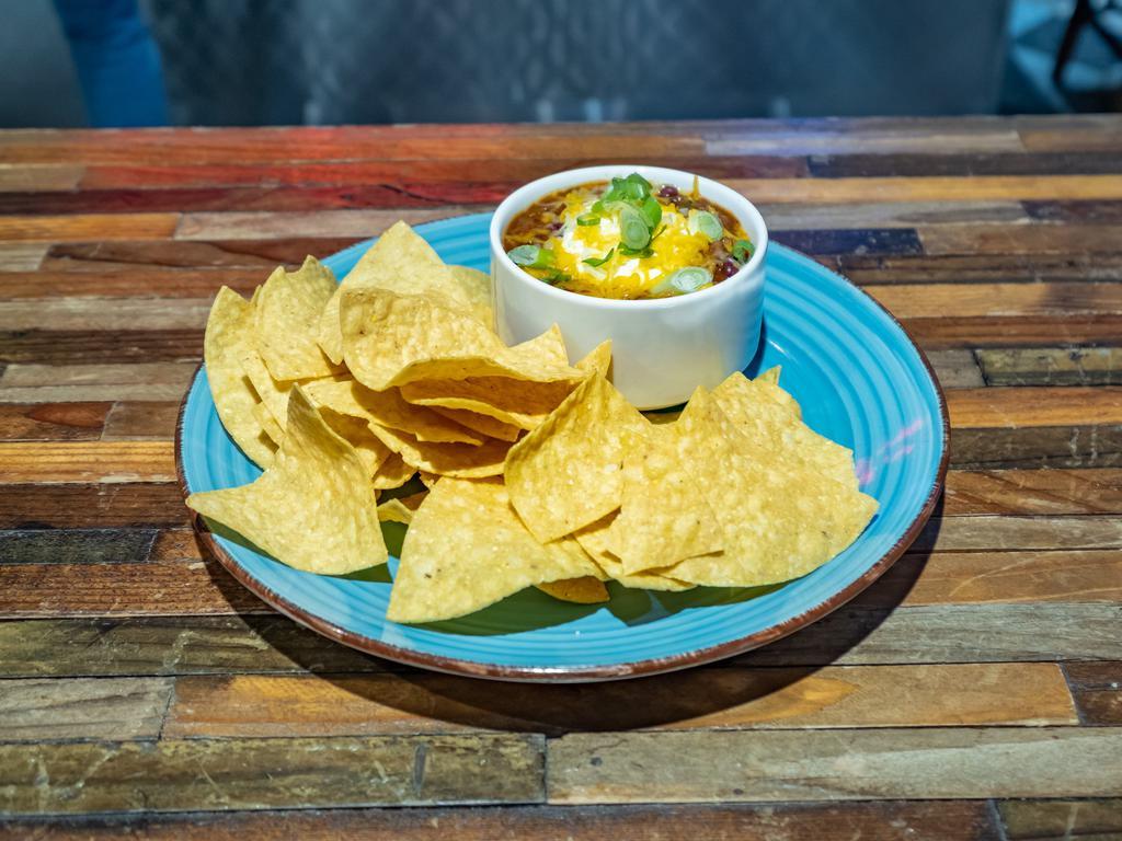 Beef Chili Bowl & Chips · Beef Chili topped with Sour Cream, Cheddar Cheese, and Green Onions. Served with a side of Tortilla Chips. Chili contains Beef, Red Kidney Beans, Peppers, Tomato.