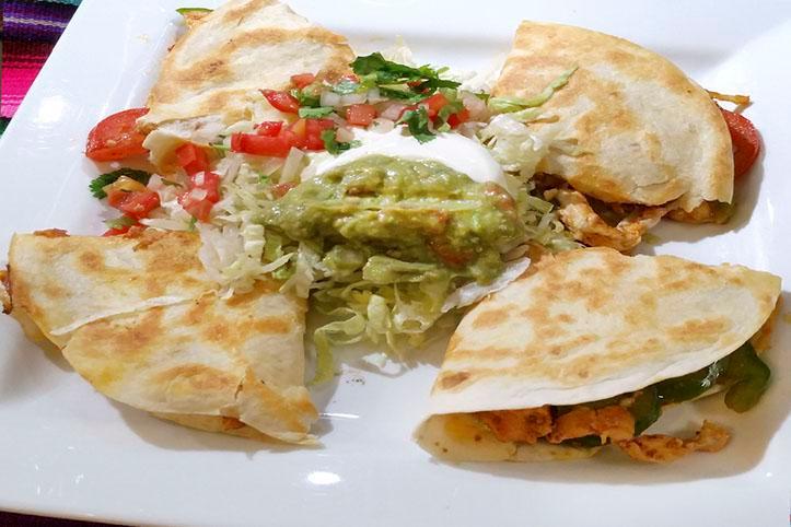 Quesadilla Ranchera · Choice of chicken or steak, mixed with bell peppers, onions, tomatoes, and cheese. Served in 2 flour tortillas and guacamole, lettuce, sour cream, and fresh tomatoes.