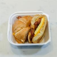 Croissant Breakfast Sandwich with Meat ·  Eggs, cheddar cheese with bacon, sausage or ham on a flaky butter croissant.