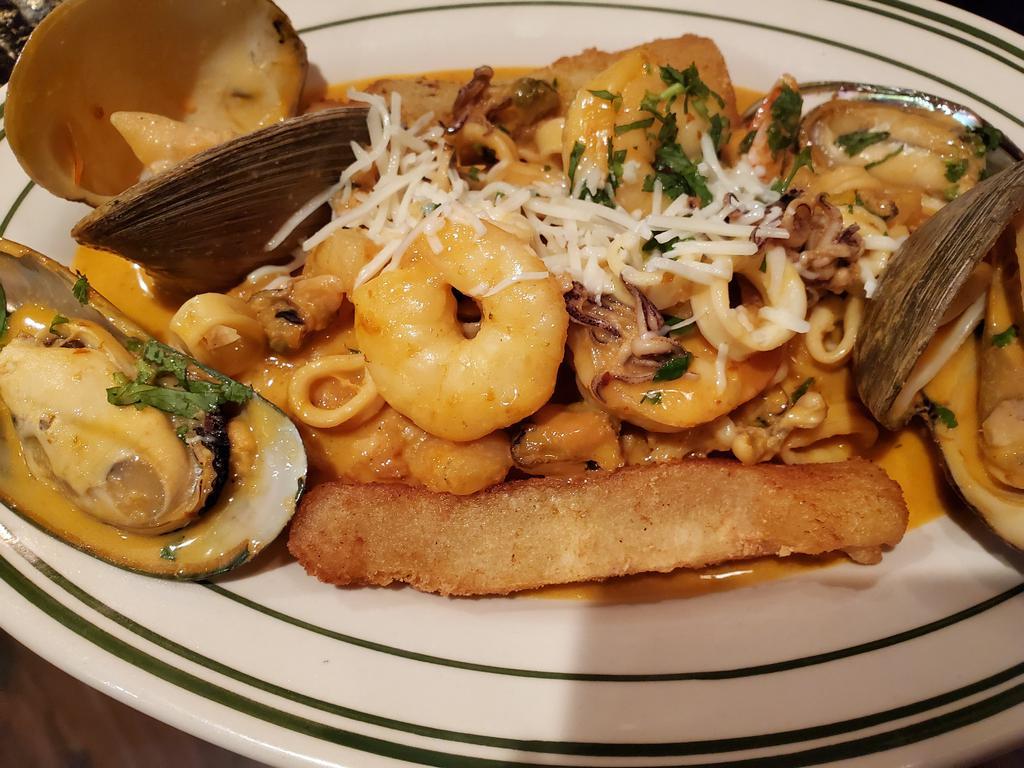 Pescado a lo Macho · Freshly fried fish fillet topped with shrimps, mussels, calamari & clams in creamy aji panca sauce served with jasmine rice & fried yuca.