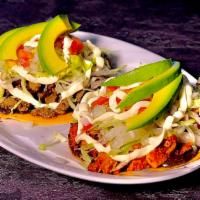 Tostada (1) · Crunchy Deep Fried Tortilla Topped With your Choice of Meat, Refried Bean Spread, Cotija Che...