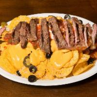 Steak Nachos · Includes black olives, tomatoes, jalapenos, sour cream, salsa, nacho cheese and shredded che...