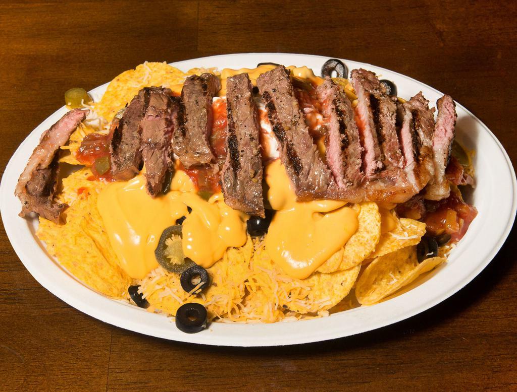 Steak Nachos · Includes black olives, tomatoes, jalapenos, sour cream, salsa, nacho cheese and shredded cheese.