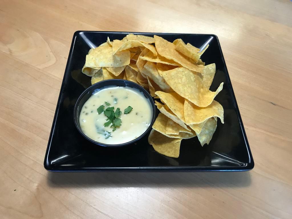 Queso Dip · Slightly spicy white cheese dip with chopped jalapenos and red peppers. With fresh made tortilla chips.