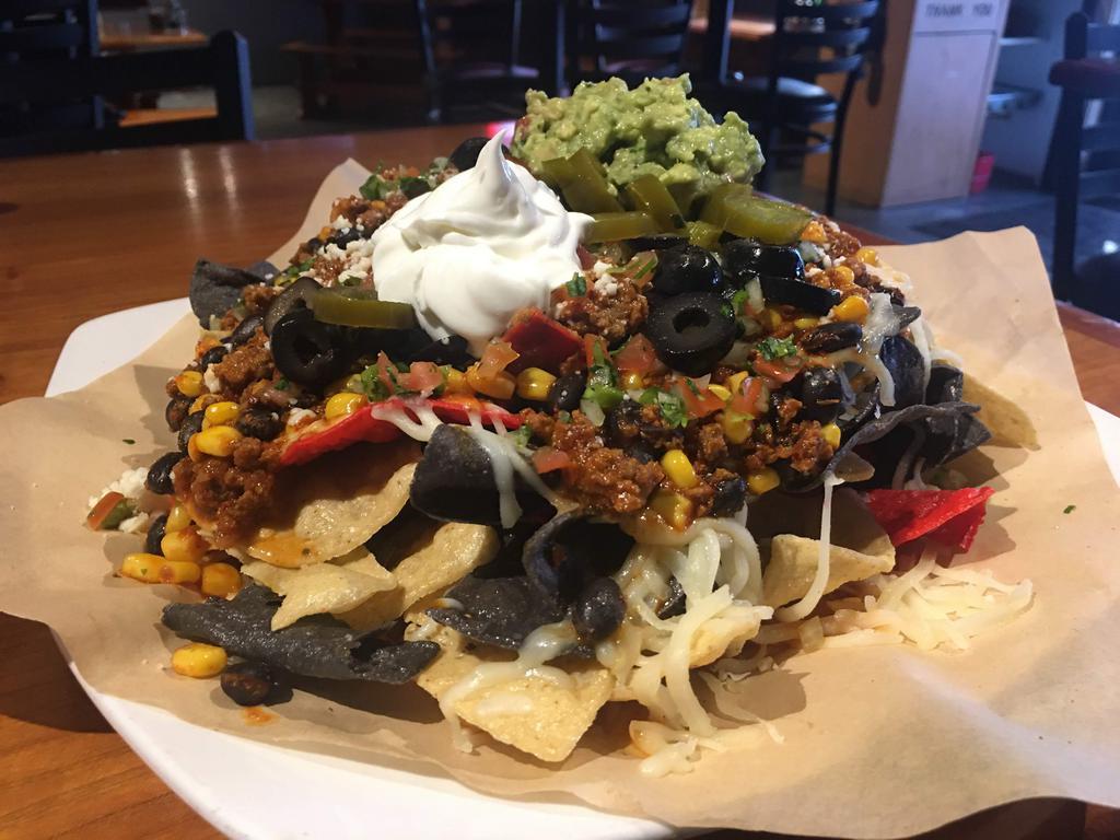 Deluxe Nachos · Choice of ground beef , shredded chicken or pulled pork. Topped with pico de gallo, jalapenos, corn, black beans and queso fresco. Served with sour cream.