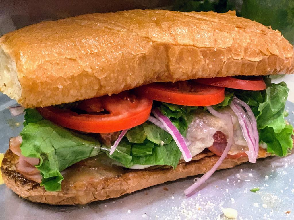 Italian Sub · Cold Sub with ham, salami, and capicola topped with lettuce, tomato, red onion, and Italian dressing on an Italian hoagie.