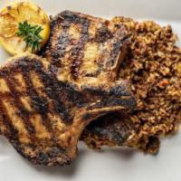 Grilled Pork Chops · Two grilled pork chops served over a bed dirty rice with collard greens
