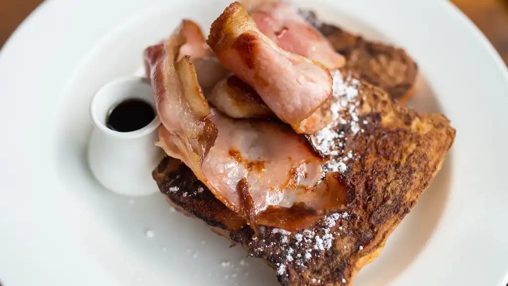 Ham French Toast with Syrup · Fresh fluffy French toast topped with slices of ham and syrup.